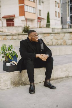 Frustrated black fired man itting outside with box