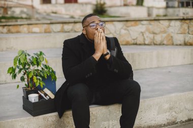 Frustrated black fired man itting outside with box