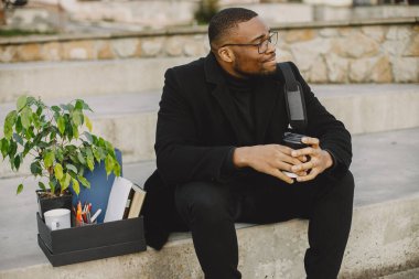 Frustrated black fired man itting outside with box