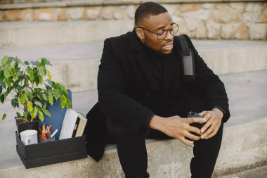 Frustrated black fired man itting outside with box