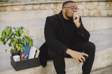 Frustrated black fired man itting outside with box