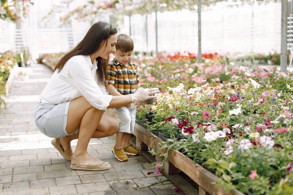 Mamá ayuda a su hijito a plantar flores en la maceta en el green — Foto de Stock