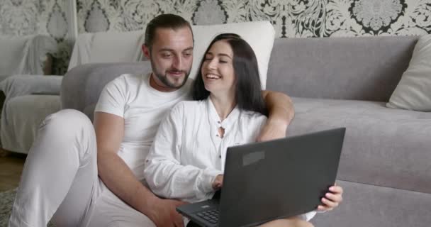 Unga europeiska par som använder bärbar dator sittandes på golvet hemma — Stockvideo