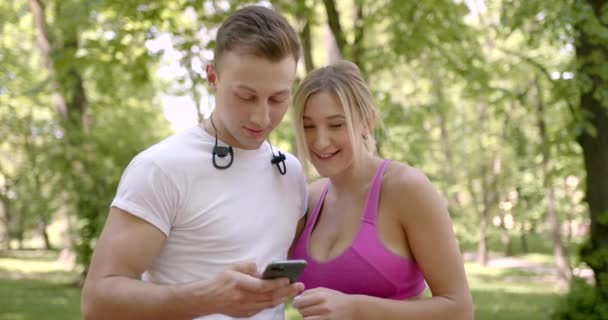 Esporte casal amoroso no parque usando smartphone — Vídeo de Stock