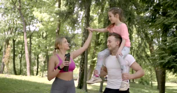 Deportiva familia haciendo sentadillas en un parque verde — Vídeos de Stock