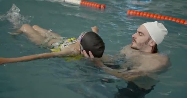 Дівчина вчиться плавати з тренером у центрі відпочинку — стокове відео