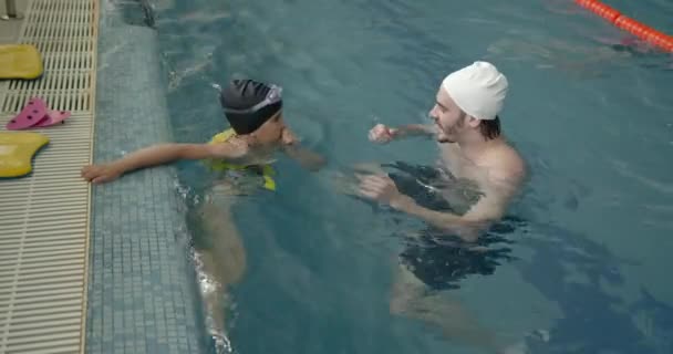 Menina aprendendo a nadar com o treinador no centro de lazer — Vídeo de Stock