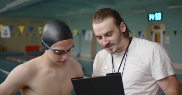 Manlig tränare och simmare pratar vid poolen — Stockvideo