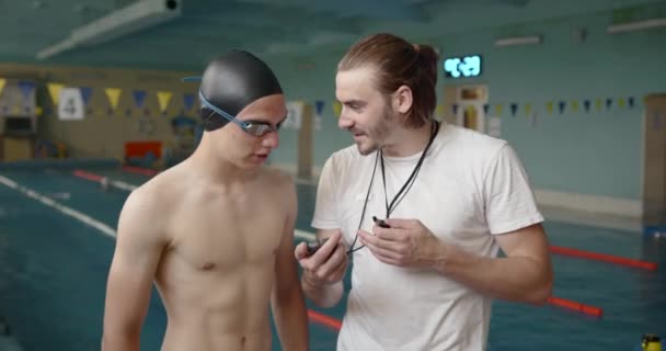 Manlig tränare och simmare pratar vid poolen — Stockvideo