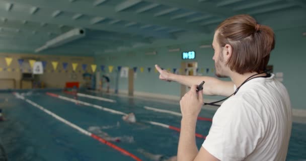 Тренер тренируется с пловцом в крытом бассейне — стоковое видео