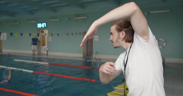 Тренер тренируется с пловцом в крытом бассейне — стоковое видео