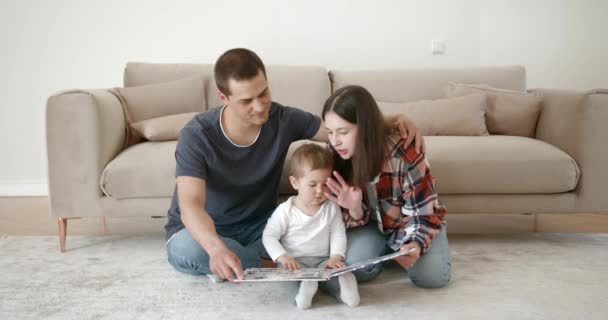 Jovem família feliz com bebê menina ler crianças livro — Vídeo de Stock