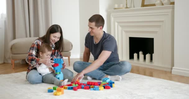 Een gelukkige moeder en vader met baby daugter spelen thuis — Stockvideo