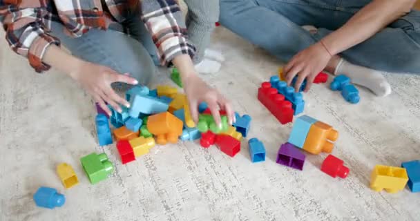 Ouders ontwarren speelgoed blokken op de vloer — Stockvideo