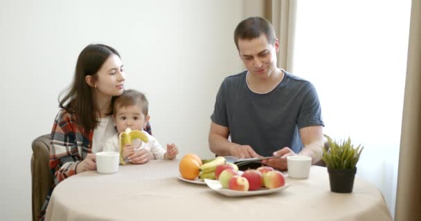 Junge süße Familie mit kleiner Tochter frühstückt — Stockvideo