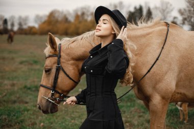 Sarışın, güzel bir kadın ve tarlada kahverengi bir at.