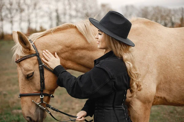 Piękna blondynka z blond włosami i brązowym koniem na polu — Zdjęcie stockowe