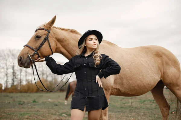 Bella donna bionda con i capelli biondi e un cavallo marrone nel campo — Foto Stock