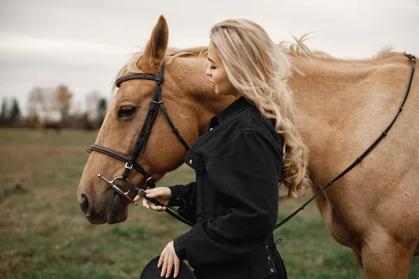 Beautiful blonde woman with blonde hair and a brown horse in the field — Stock Photo, Image