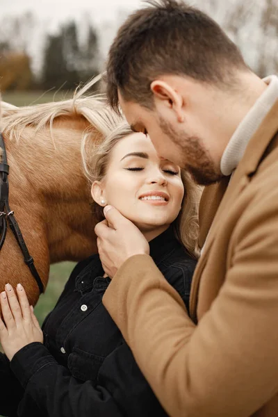 Pareja romántica con un caballo marrón en el campo — Foto de Stock