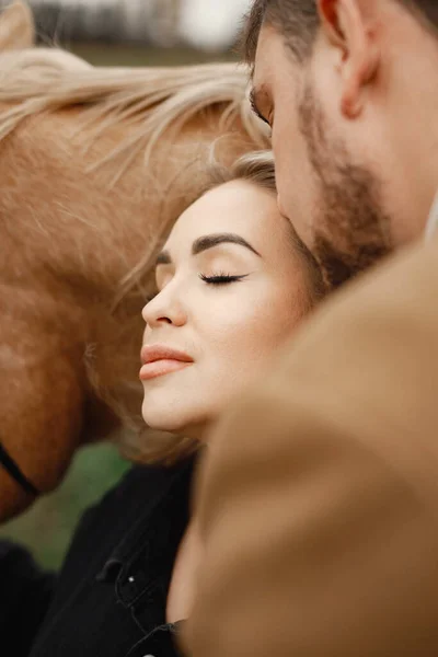 Romantisch koppel met een bruin paard in het veld — Stockfoto