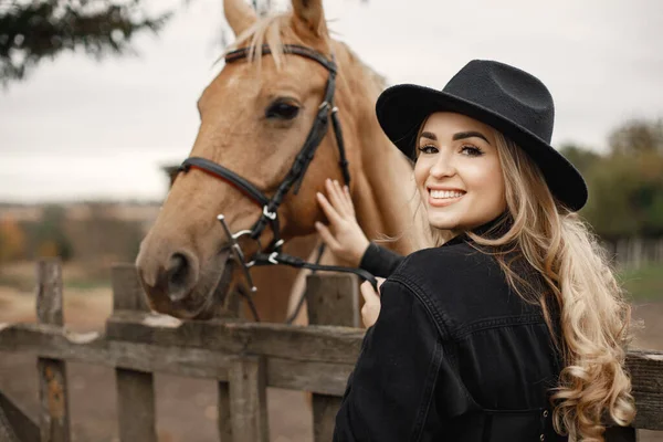 Mulher tocando um cavalo marrom behinde a cerca em uma fazenda — Fotografia de Stock