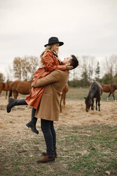 Casal romântico andando no campo com cavalos — Fotografia de Stock