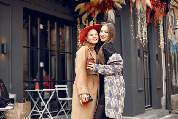 Две молодые девушки стоят рядом с кафе и обнимаются. — стоковое фото
