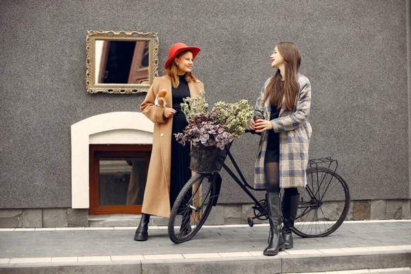 Дві молоді дівчата стоять біля велосипеда з квітами і розмовляють — стокове фото
