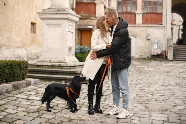 Krásný pár objímání při procházce se svým psem v ulici starého města — Stock fotografie