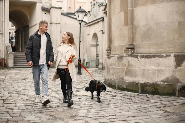 Encantador casal de mãos dadas enquanto caminha com seu cão na rua da cidade velha — Fotografia de Stock
