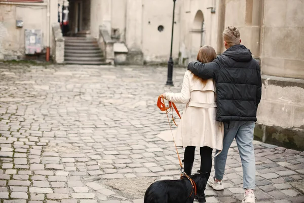 Zadní strana fotografie krásného páru objímání při chůzi se svým psem — Stock fotografie