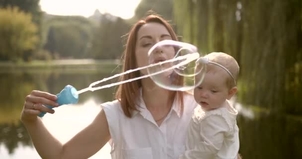 Счастливая мать, пускающая мыльные пузыри с ребенком — стоковое видео