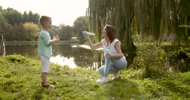 Ευτυχισμένη μητέρα φυσάει σαπουνόφουσκες με παιδί — Αρχείο Βίντεο