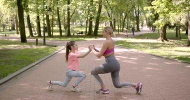 Anne ve kızı halka açık parkta spor yapıyor.