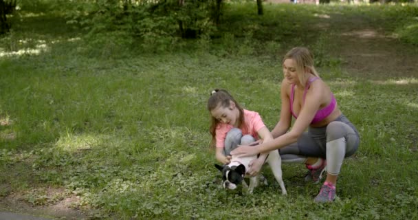 Matka i córka pieszczą psa w parku — Wideo stockowe