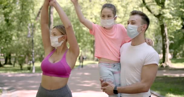Спортивная семья в масках, стоящая в зеленом парке — стоковое видео