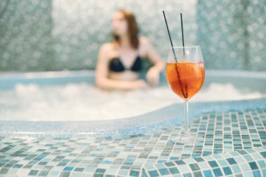 Kaplıcada mayo giyen genç bir kızın portakal suyuna odaklan.