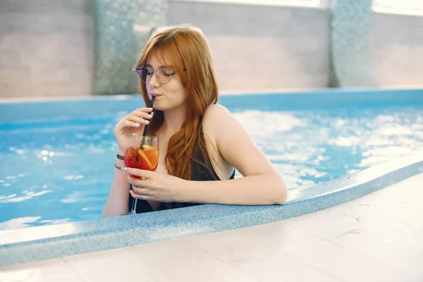 Νεαρή κοπέλα με μαγιό που χαλαρώνει στην πισίνα και κρατάει ένα κοκτέιλ — Φωτογραφία Αρχείου