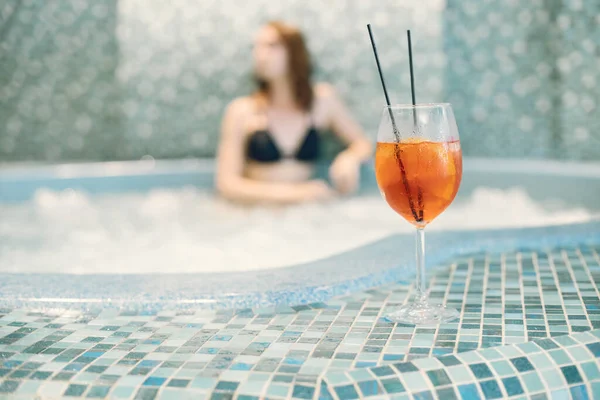 Focus sur une boisson orange d'une jeune fille en maillot de bain dans un spa — Photo