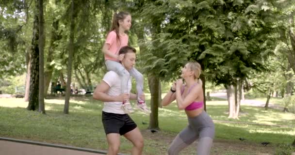 Família desportiva fazendo agachamentos em um parque verde — Vídeo de Stock