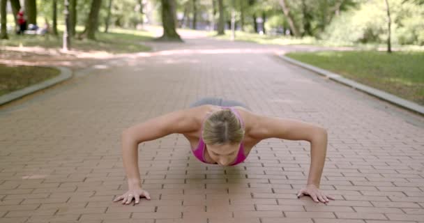 Sportowa kobieta robi pompki w letnim parku — Wideo stockowe