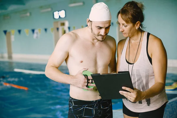 Entrenadora y nadadora hablando junto a la piscina —  Fotos de Stock
