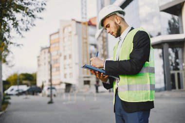 Man in builder uniform holding older. Looking at building plan. Modern city setting.
