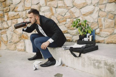 European employee got fired. He drinks alcohol from bottle.