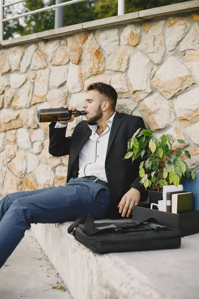 European employee got fired. He drinks alcohol from bottle.