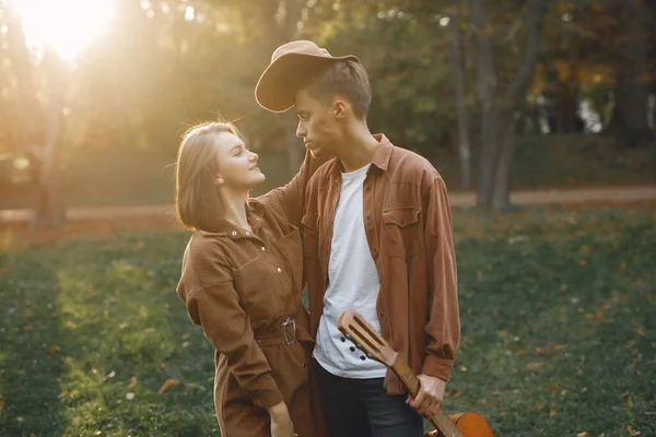 Couple in a park. Guy in a brown shirt. Golden autumn. Man with a guitar.