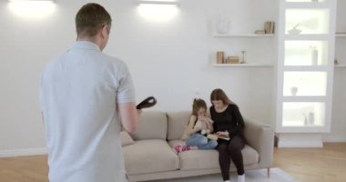 Cropped view of father with belt going to fight with wife and daughter. Mother embracing the scared child.