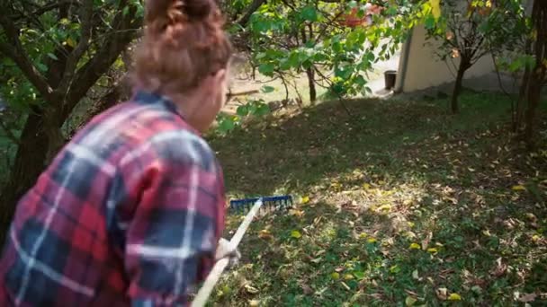 Wanita dewasa dewasa dewasa mengeluarkan daun kering dari halaman dengan garpu — Stok Video