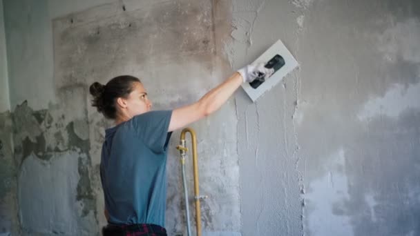 Una reparadora profesional pone un yeso en la pared con una espátula. — Vídeos de Stock